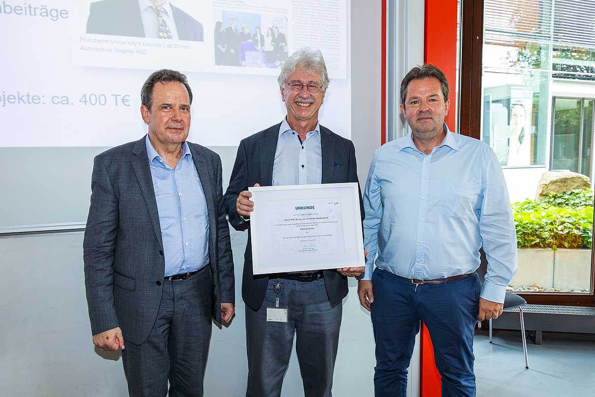 Rektor Prof. Dr. Ulrich Jautz (links) sowie Prof. Dr. Ingolf Müller (rechts), Dekan der Fakultät für Technik, gratulieren Prof. Dr. Karlheinz Blankenbach zur ersten Seniorprofessur an der Hochschule Pforzheim und lächeln in die Kamera